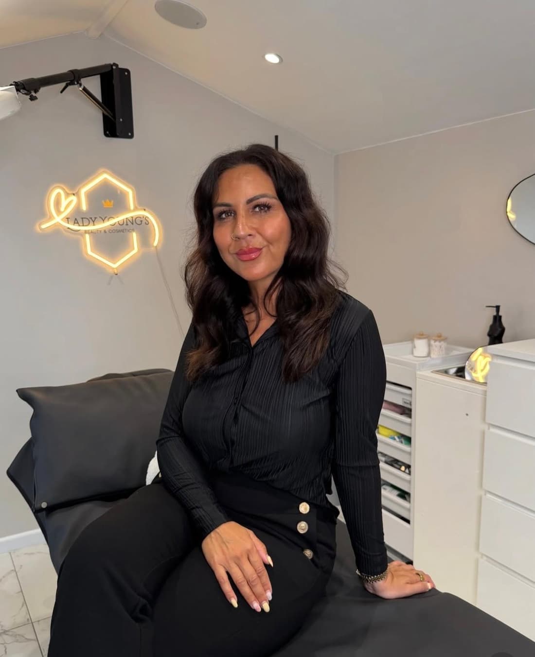 Safina Young in her private treatment studio at Lady Young's in Bracknell, beside the gold neon clinic sign